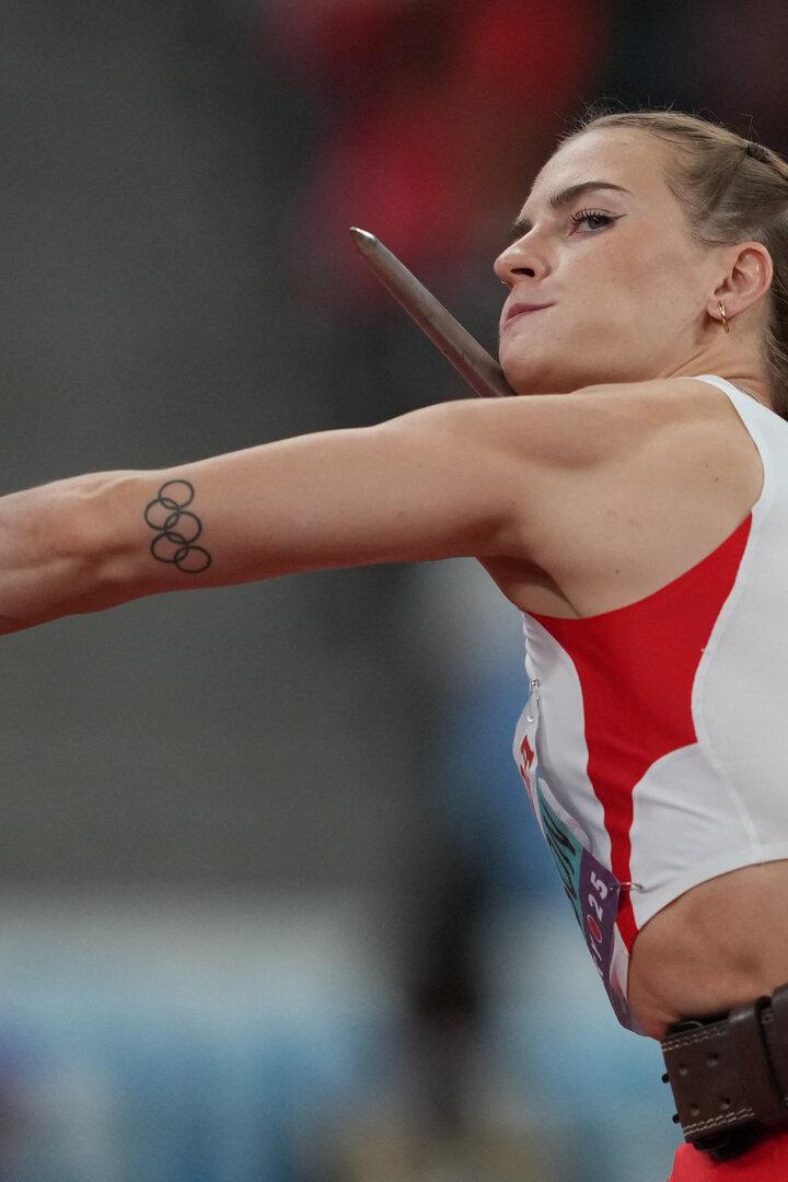 Eine Speerwerferin mit Tätowierung der olympischen Ringe bereitet sich auf den Wurf vor.