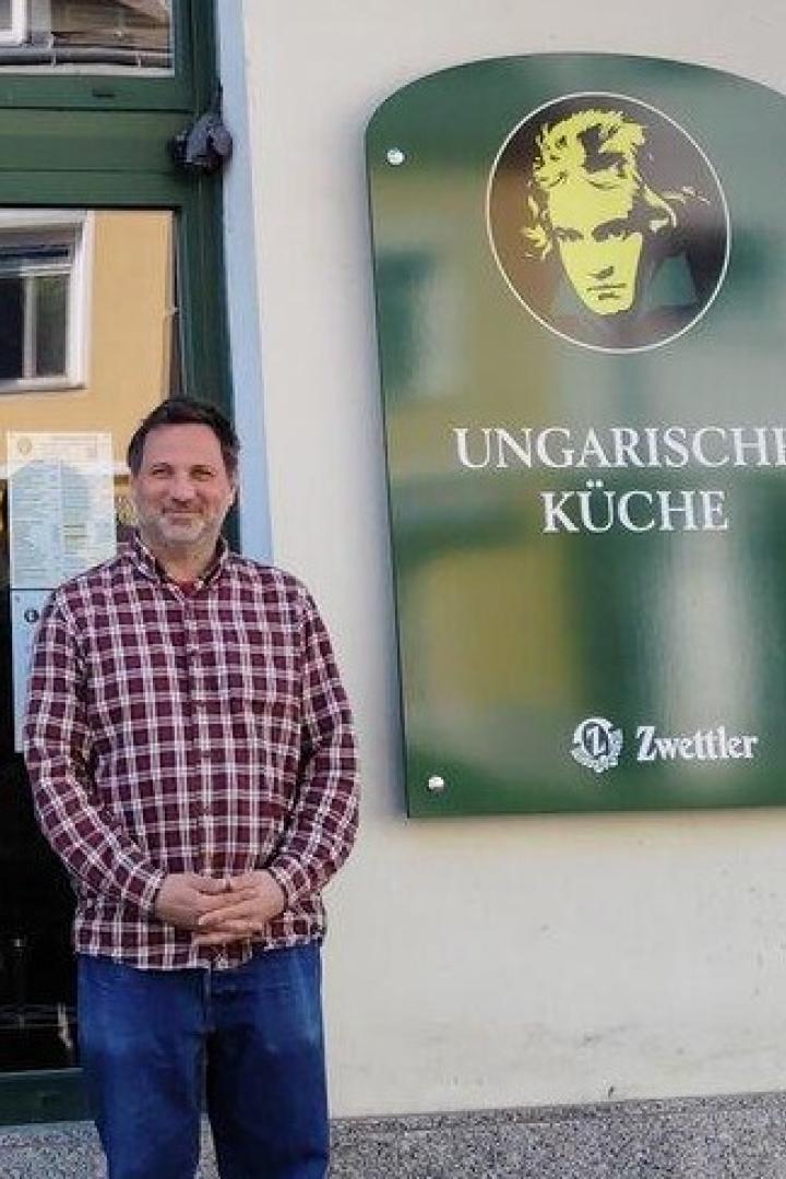 Ein Mann steht vor dem Restaurant "Ungarische Küche" mit einem Schild von Zwettler.