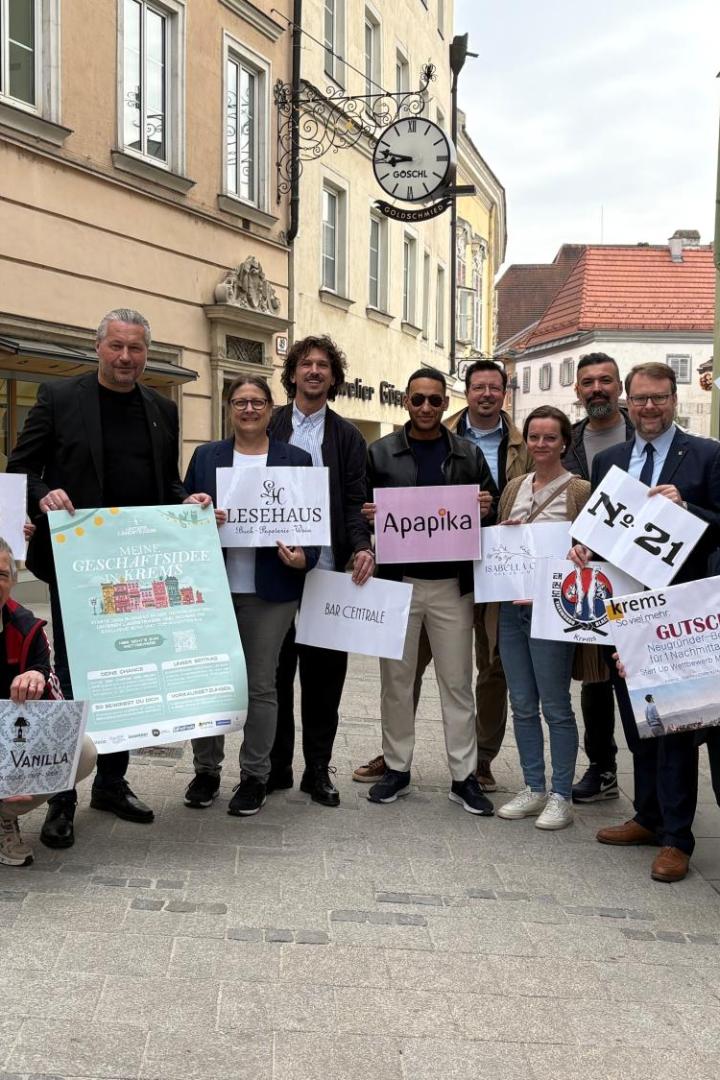 Die Gründerinnen und Gründer stehen in der Kremser Fußgängerzone, halten Plakate mit ihren Firmen in Händen und lächeln in die Kamera.