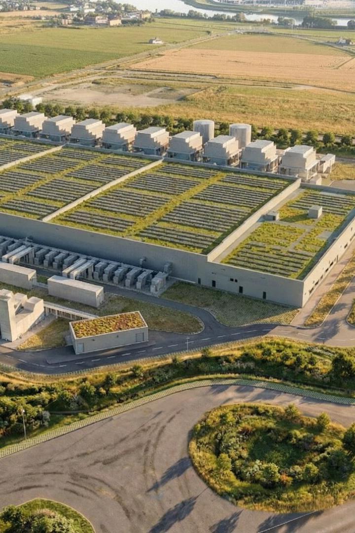 Großer Industriekomplex mit begrünten Dächern, umgeben von Feldern, Straßen und vereinzelten Bäumen.