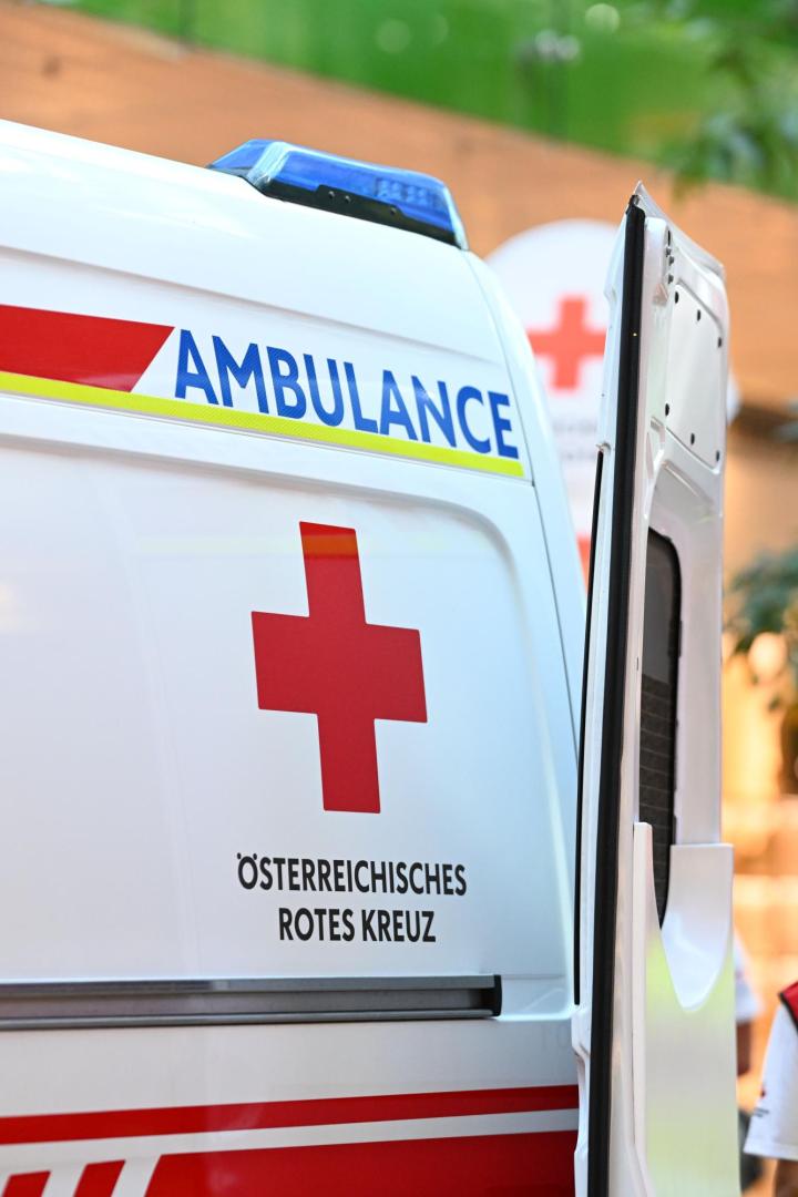 Ein Rettungswagen des Österreichischen Roten Kreuzes mit geöffnetem Heck steht im Freien.