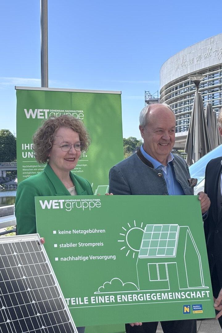 Vier Personen präsentieren ein Solarmodul und ein Schild der WET Gruppe vor einem Gebäude.