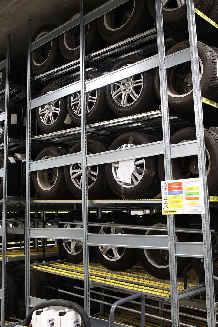 Mehrere Reihen Autoreifen mit Felgen sind ordentlich in einem Lagerregal gestapelt.