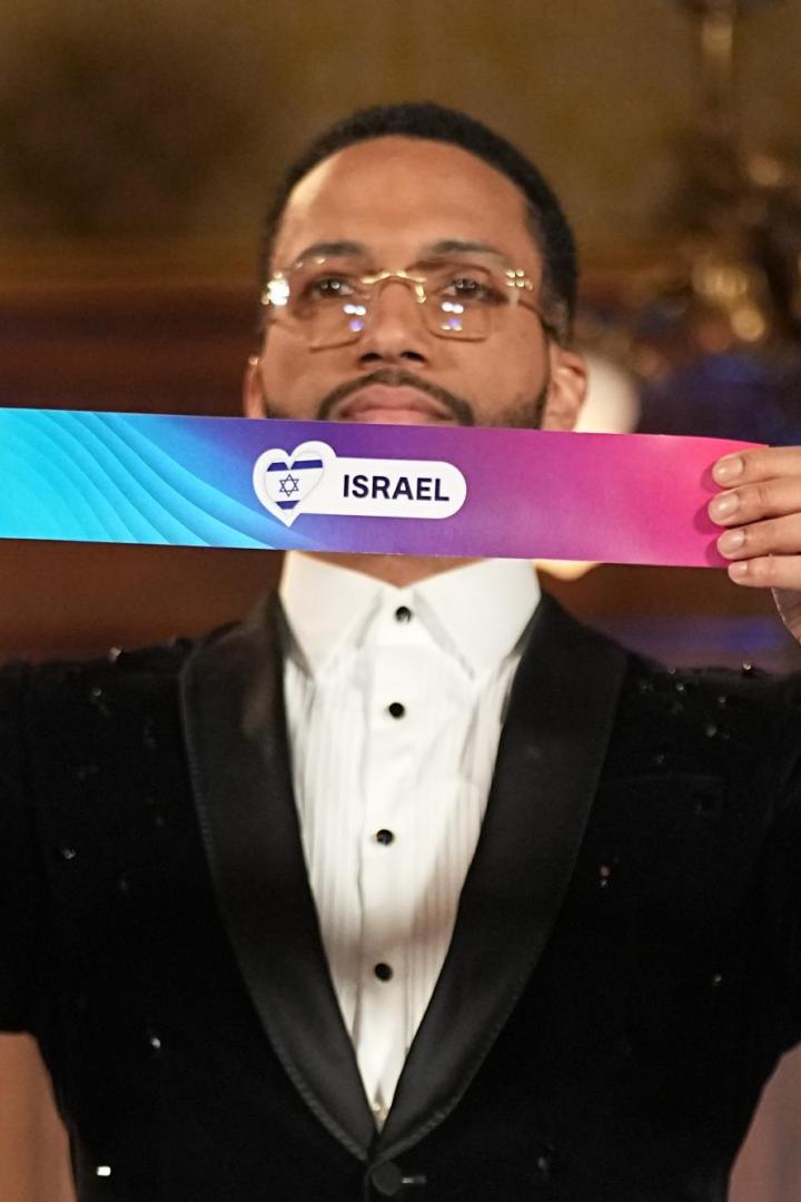 Ein Mann im Anzug hält ein farbiges Schild mit der Aufschrift „Israel“ und einem Herzsymbol mit Davidstern.