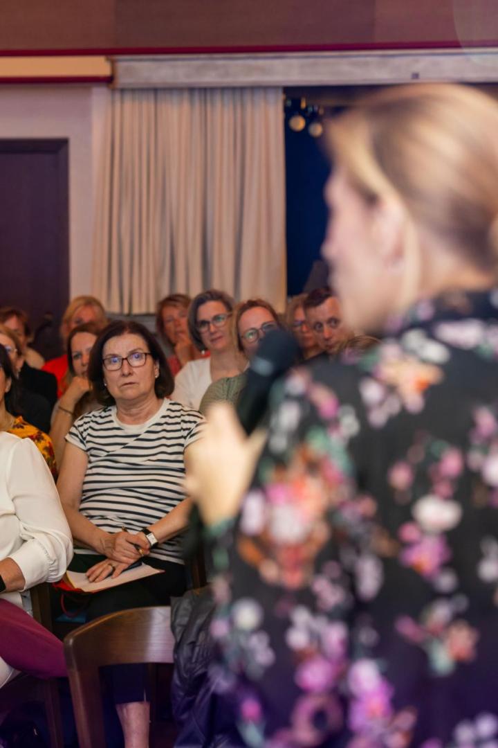 Eine Frau spricht vor einem aufmerksam lauschenden, überwiegend weiblichen Publikum.