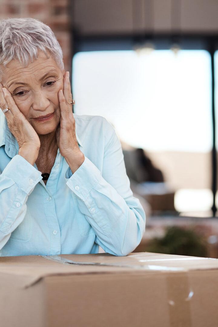 Verzweifelte Seniorin mit Umzugskartons