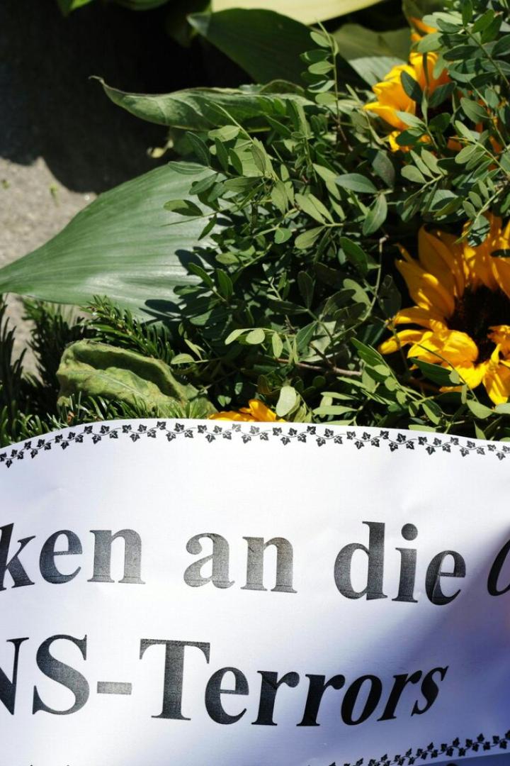 Ein Kranz mit Sonnenblumen und der Aufschrift "Im Gedenken an die Opfer des NS-Terrors" liegt auf dem Boden.