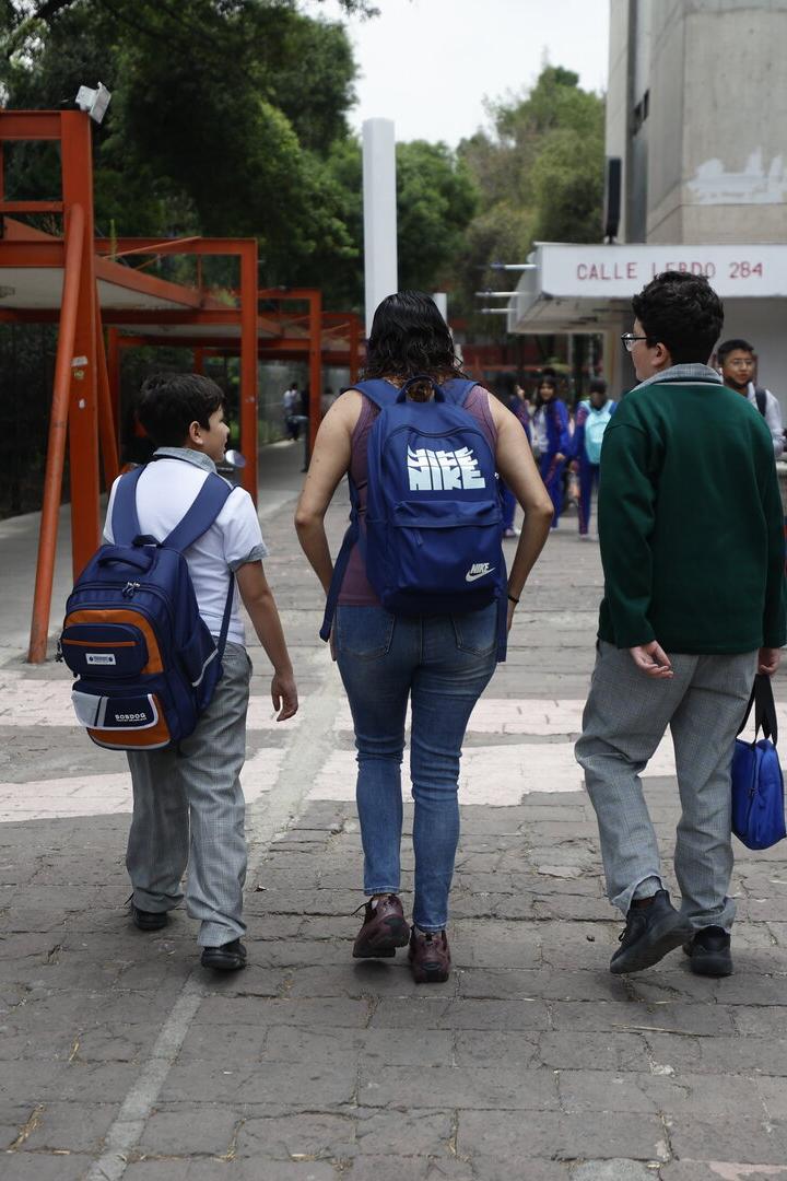 Drei mexikanische Schüler vor einer Schule.