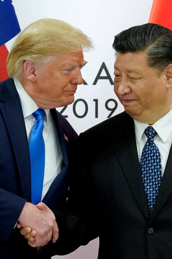 Donald Trump und Xi Jinping schütteln sich vor den Flaggen der USA und Chinas die Hände.