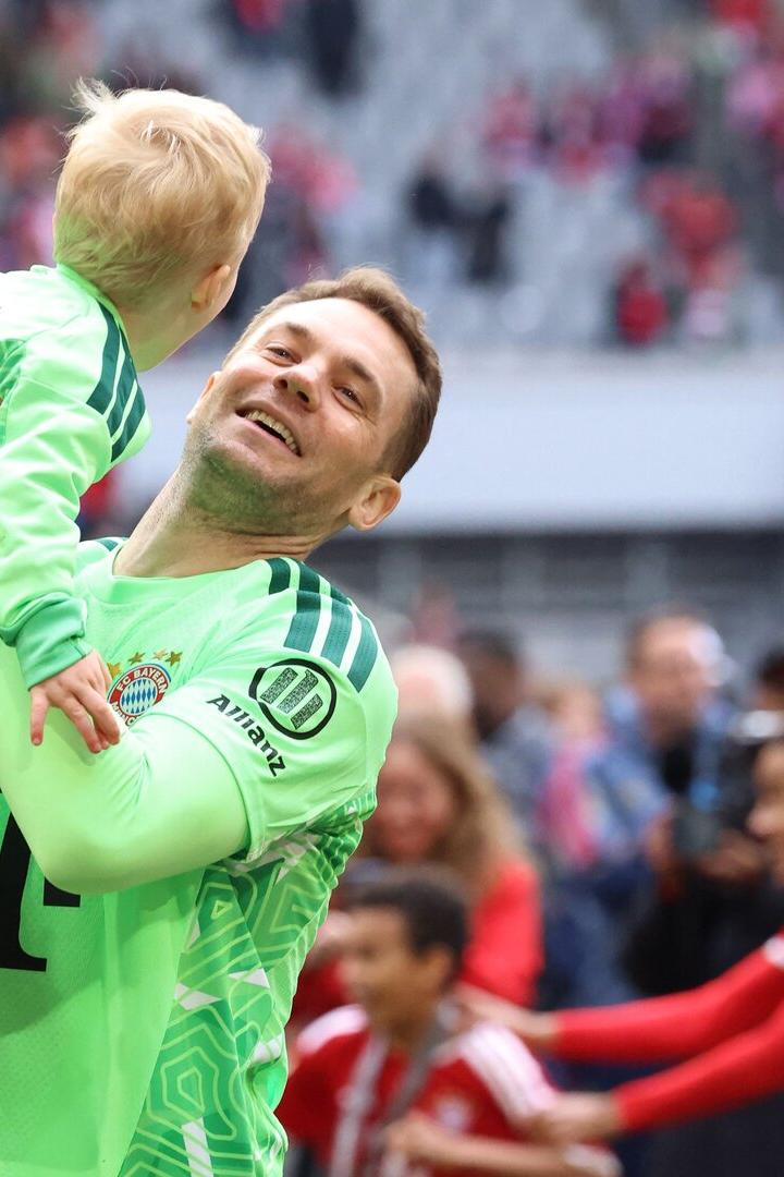 Manuel Neuer hebt ein Kind in die Höhe.