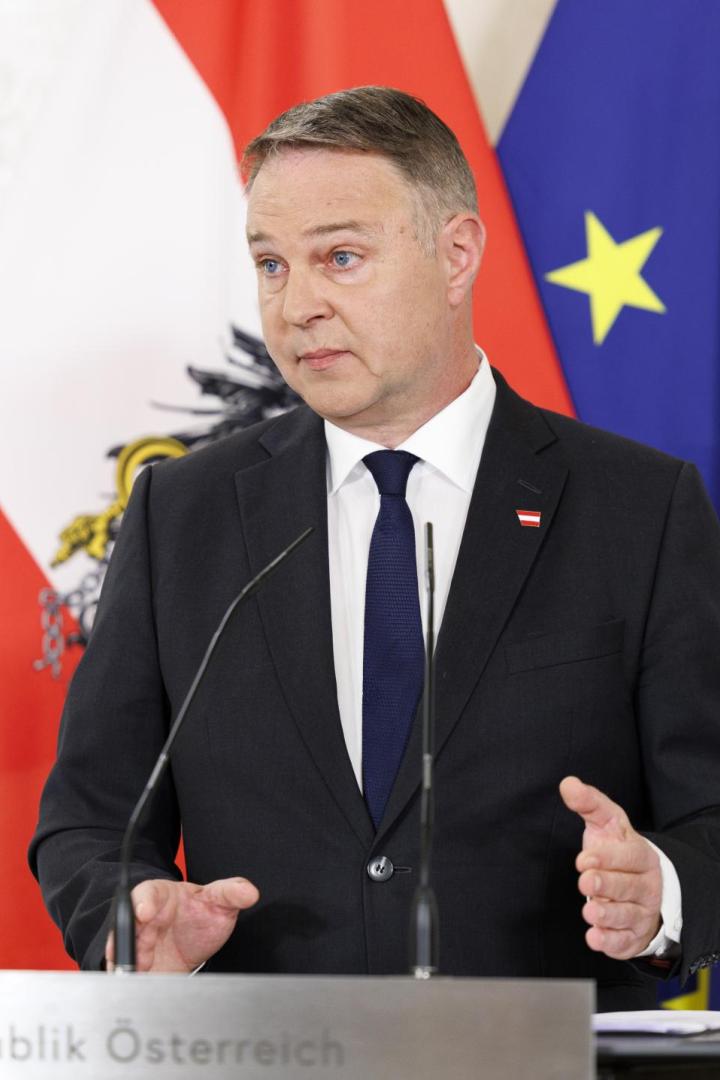 Ein Mann im Anzug spricht an einem Rednerpult vor österreichischer und EU-Flagge.