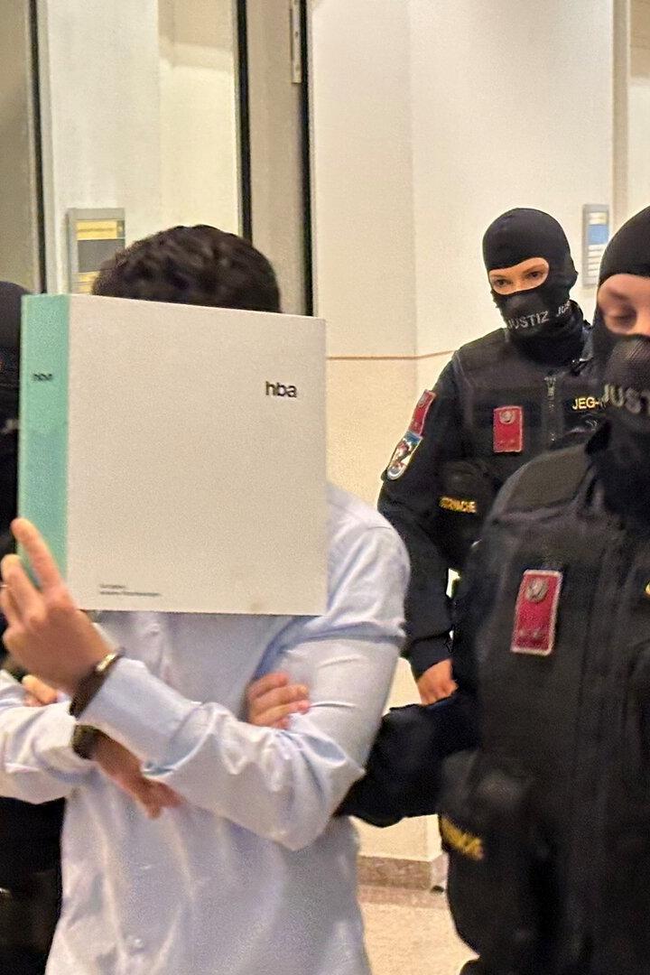 Justizwachebeamte mit Sturmhauben führen zwei Angeklagte vor
