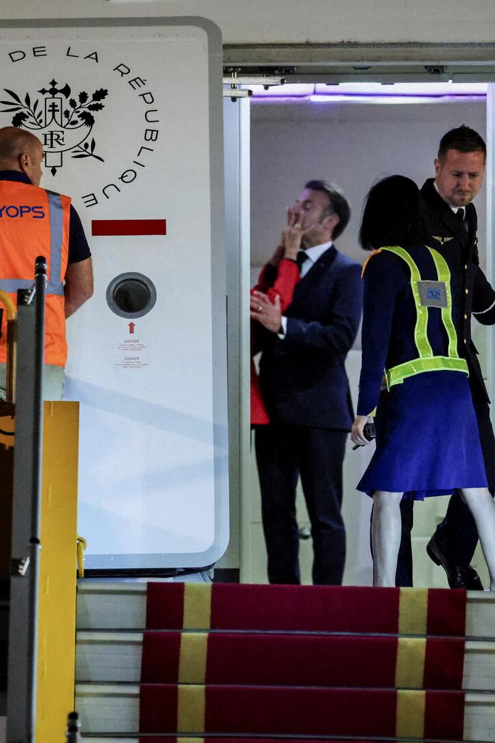 Mehrere Personen stehen an einer Flugzeugtür mit rotem Teppich und Sicherheitswesten, während sie ein- oder aussteigen.