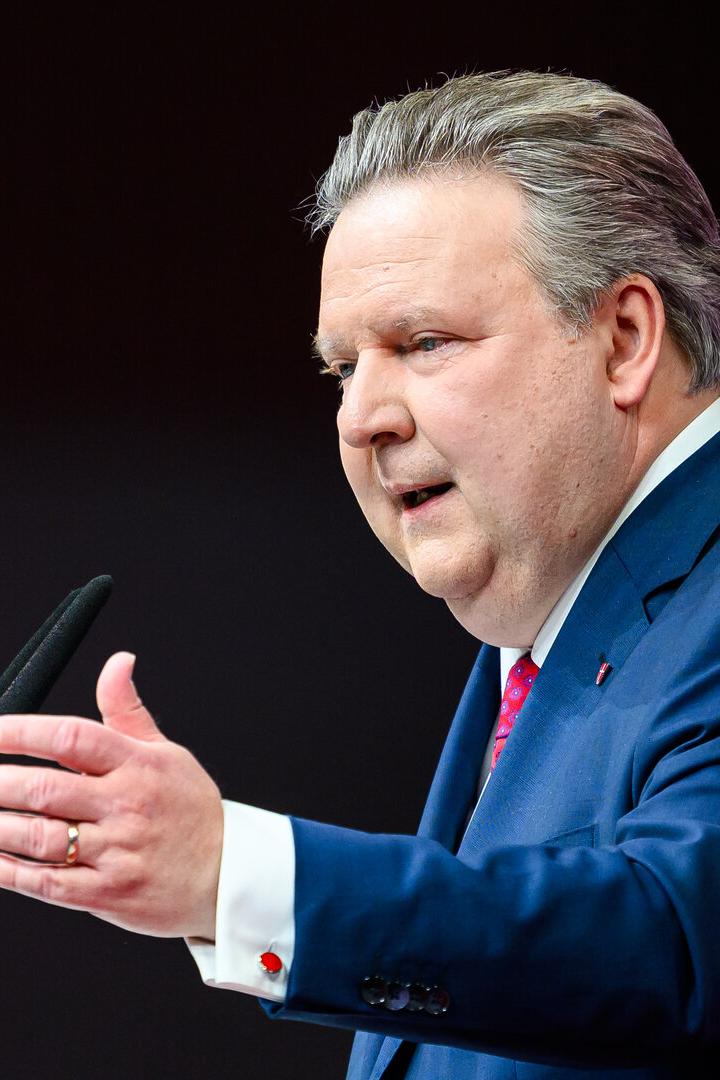 Michael Ludwig im blauen Anzug spricht gestikulierend an einem Mikrofon vor dunklem Hintergrund.