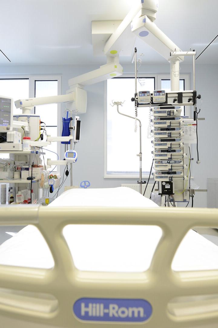 Krankenhauszimmer mit leerem Bett, medizinischen Geräten, Monitoren und Infusionspumpen in heller Umgebung.