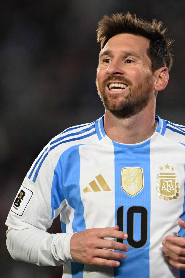 Lionel Messi lächelt in seinem weiß-hellblauen Trikot der argentinischen Nationalmannschaft mit der Rückennummer 10 auf dem Spielfeld.