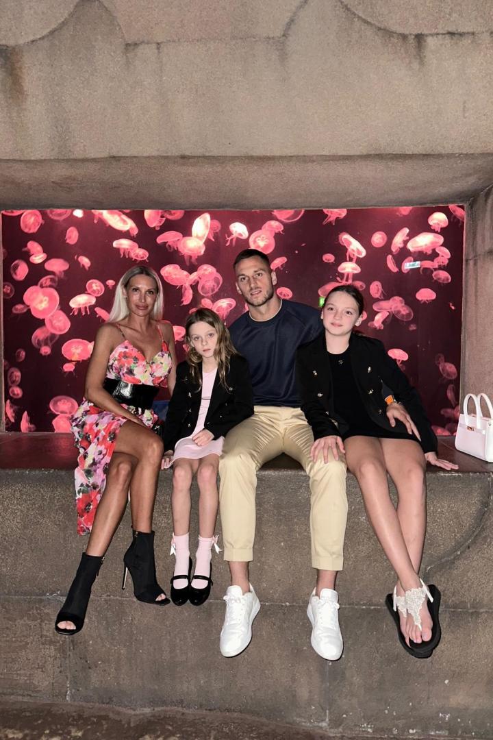 Marko Arnautovic sitzt mit Partnerin Sarah und den beiden Töchtern Alicia und Emilia vor einem Aquarium mit Quallen.