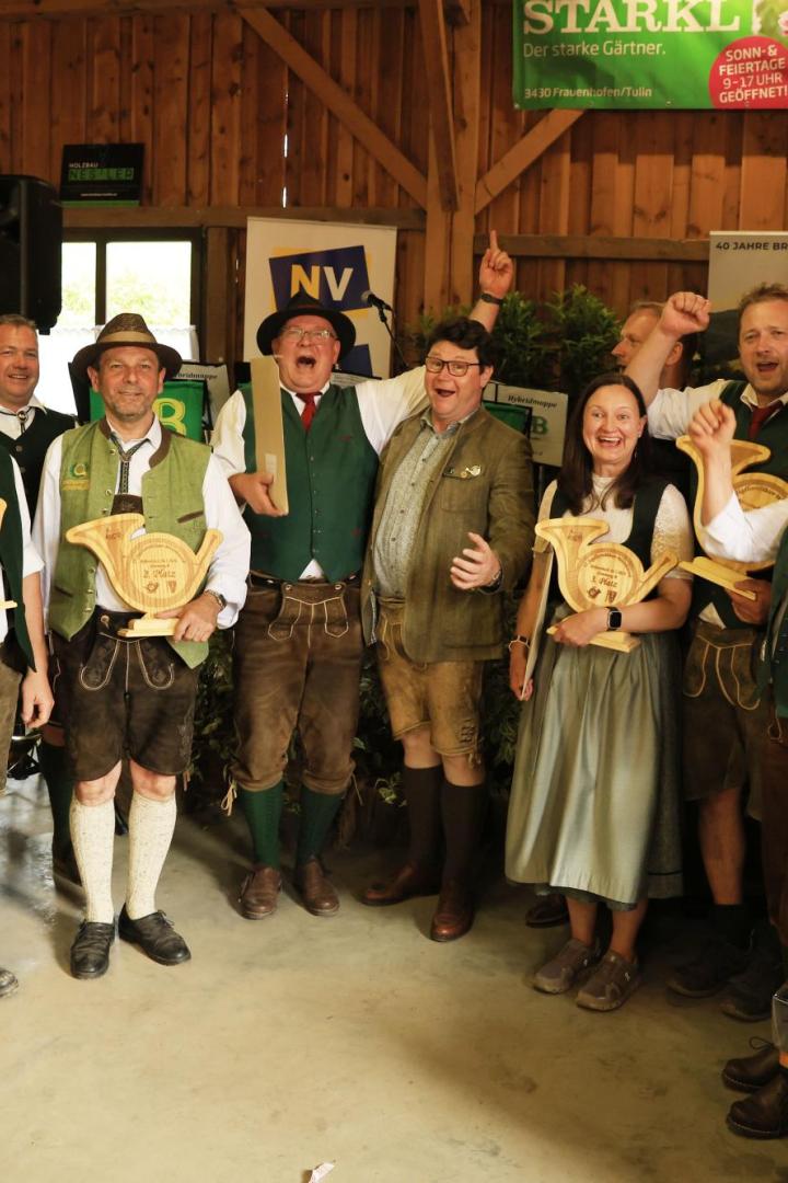 Eine Gruppe in Tracht feiert bei einer Veranstaltung des Breitenfurter Jagdklubs mit Trophäen in einer Holzhalle.
