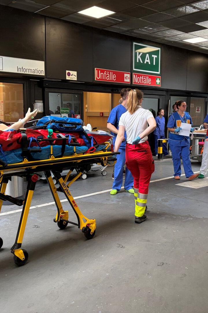 Eine Simulationspuppe wird von Notfallsanitätern in die Unfallambulanz transportiert