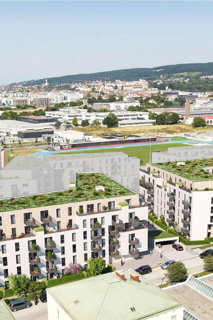 Luftaufnahme eines Stadtviertels mit geplanten Wohnhäusern, Straßen und Hügeln im Hintergrund.