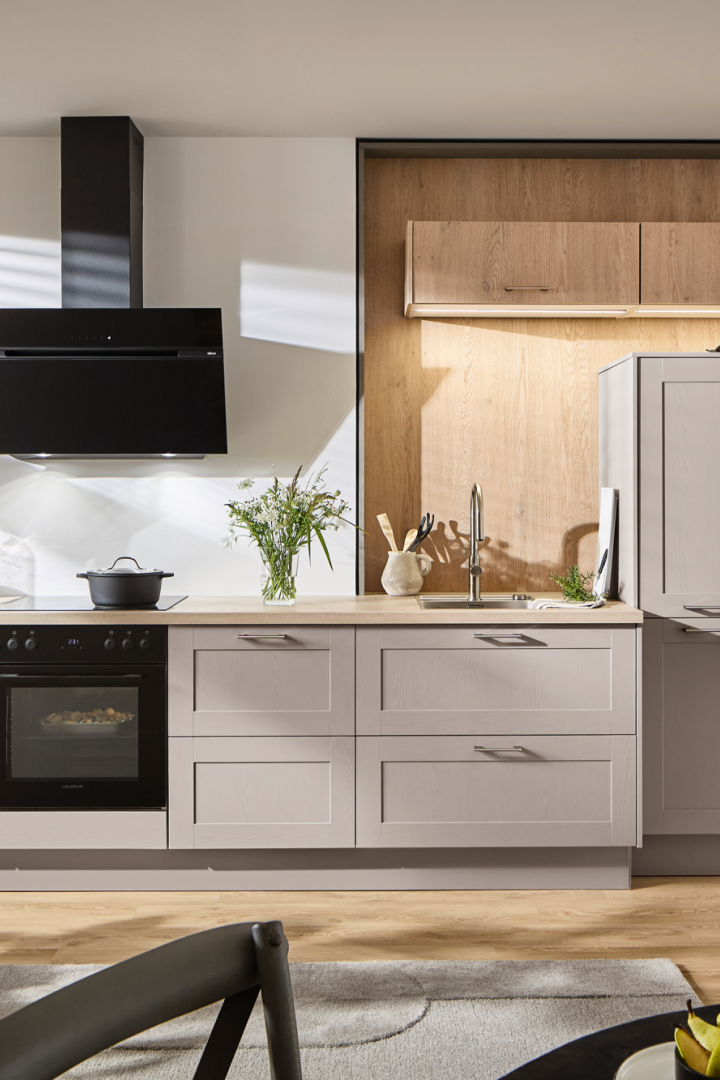 Moderne Küche in Beige und Holz mit matten Fronten und schwarzer Dunstabzugshaube.