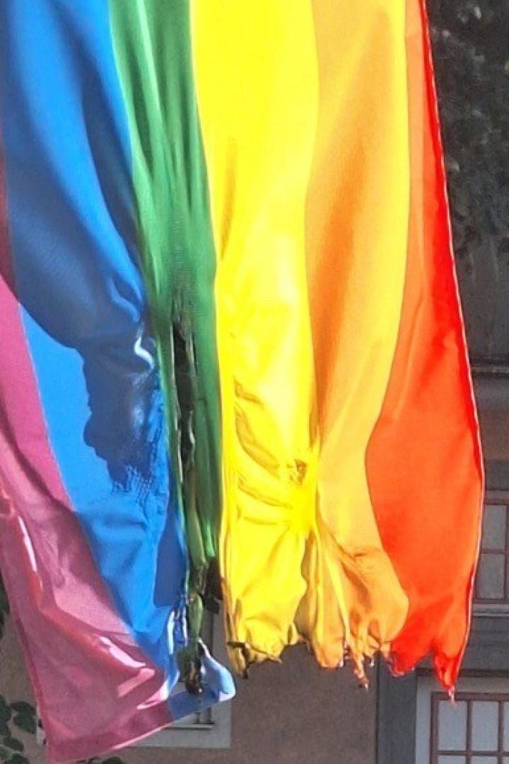 Zerstörte Regenbogenfahne vor einem Haus.