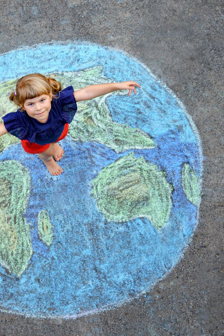 Little preschool girl with earth globe painting with colorful chalks on ground. Positive toddler child. Happy earth day concept. Creation of children for saving world, environment and ecology.