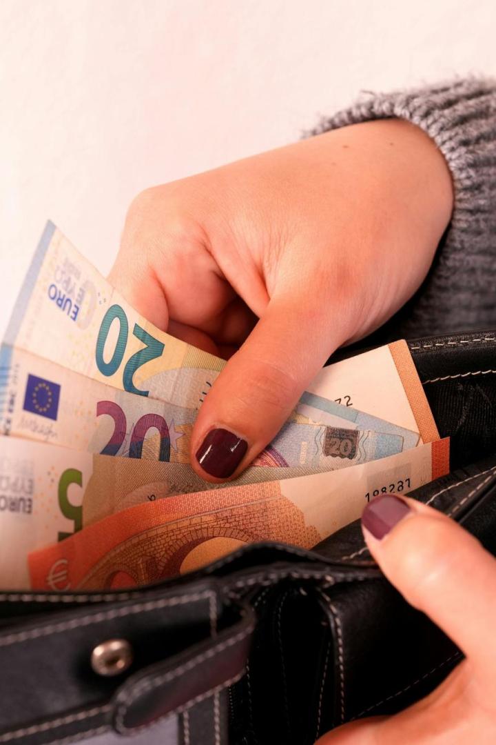 Eine Frau, die Gelscheine in ihre Börse steckt.