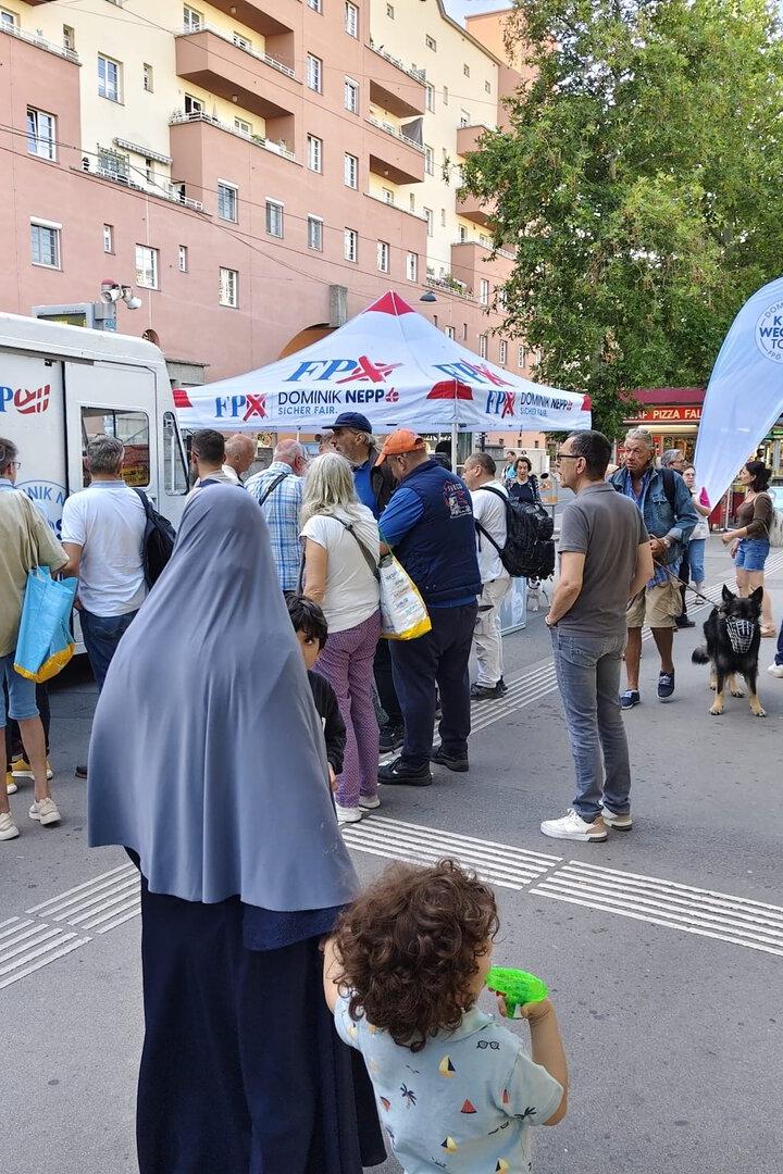 Menschen stehen vor einem Imbisswagen bei einer Wahlkampfveranstaltung der FPÖ mit Dominik Nepp in Wien.