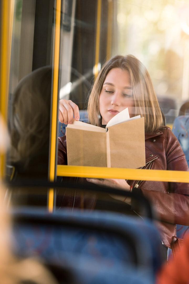 girl reading book in bus