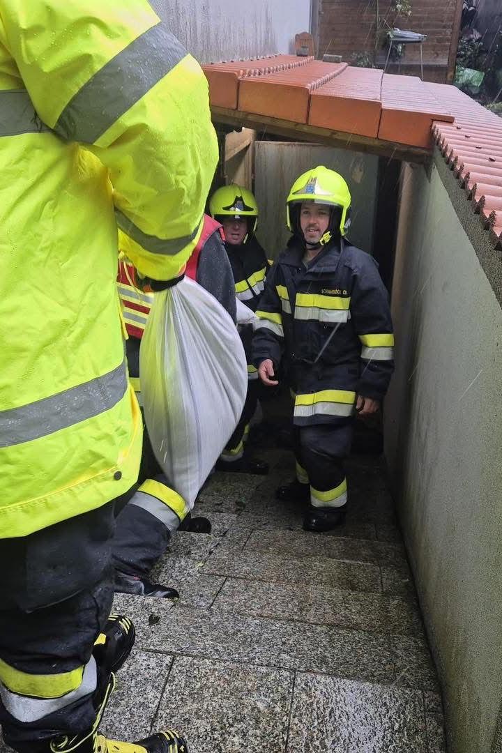 Feuerwehrleute tragen Sandsäcke durch einen engen Kellerabgang.