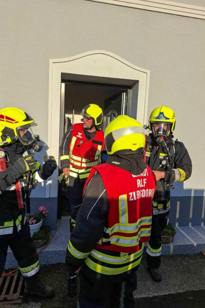 Feuerwehrleute in Atemschutz vor einem Haus nach dem Brand.