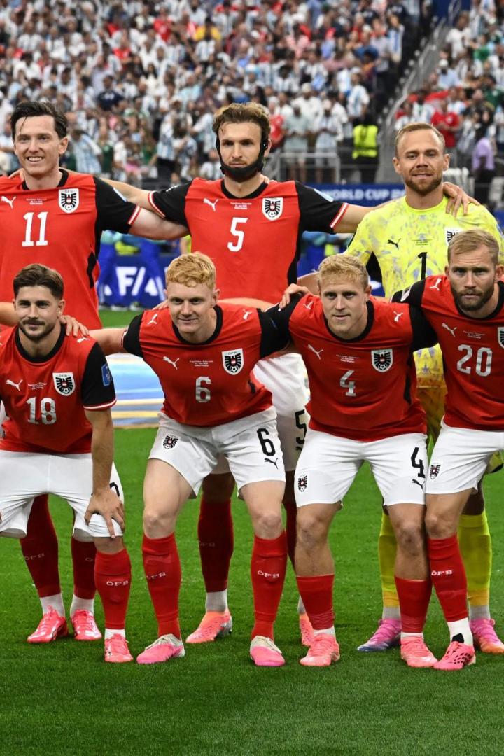 Österreichische Fußballmannschaft posiert vor dichtem Stadionpublikum vor dem Spiel.