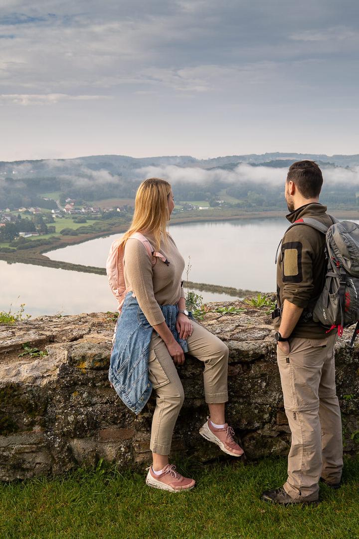 Zwei Personen stehen vor einer Steinmauer