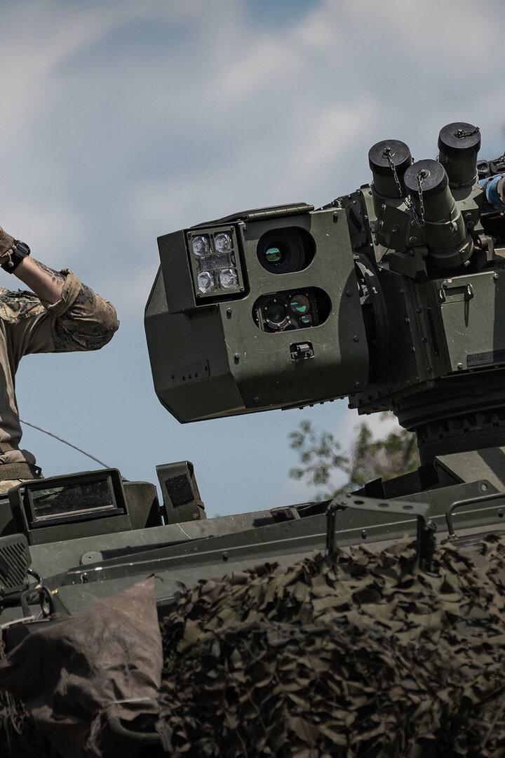 Soldat mit Feldstecher sitzt auf einem Panzer