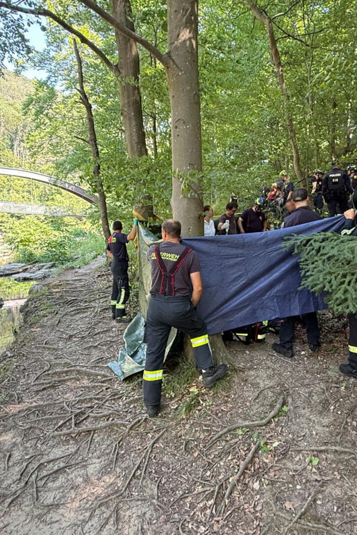 Feuerwehrleute schirmen eine Unfallstelle neben einem Fluß ab