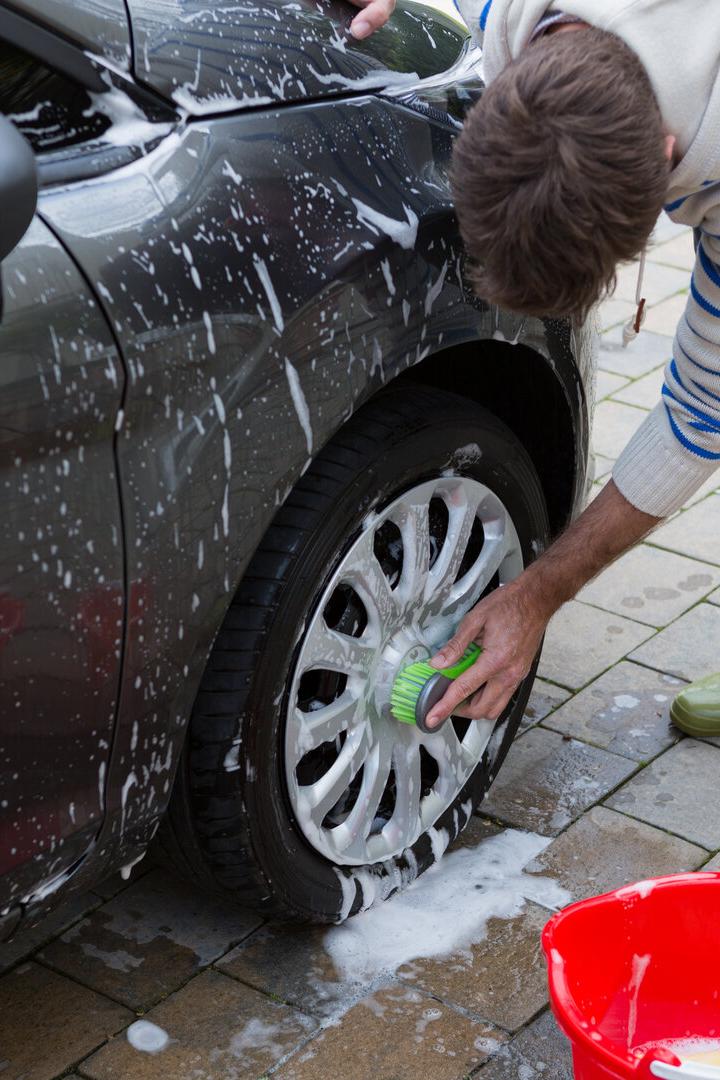 Auto service staff washing a car tyre with sponge