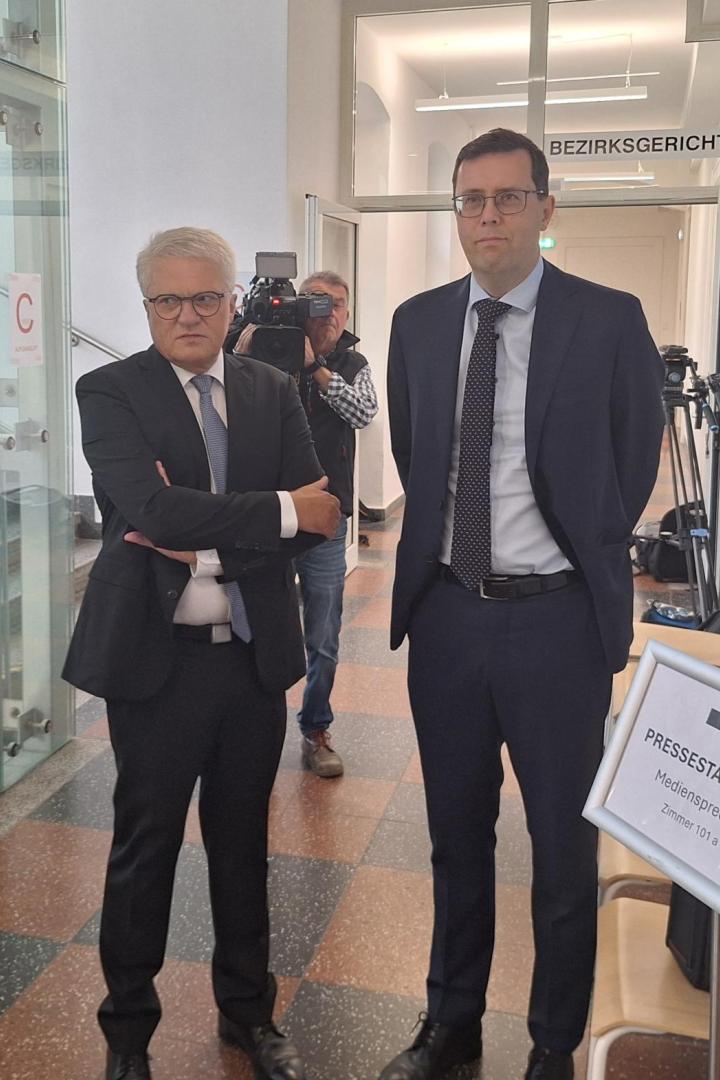 Zwei Männer in Anzügen vor einem Gerichtssaal