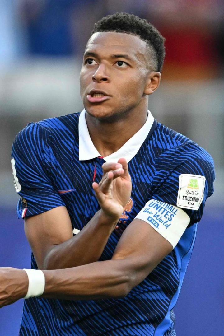 Kylian Mbappé klatscht in die Hände, während er das blaue Trikot der französischen Nationalmannschaft trägt.