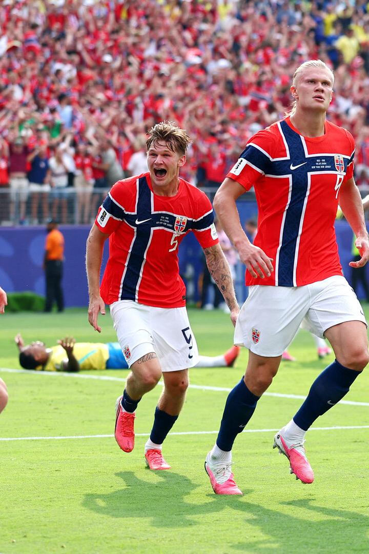Erling Haaland und seine norwegischen Teamkollegen jubeln nach einem Tor auf dem Fußballfeld vor einer großen Zuschauermenge.