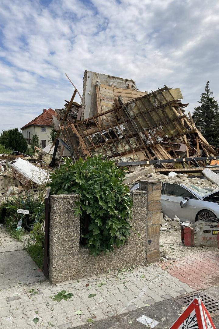 Ein eingestürztes Gebäude liegt in Trümmern, wobei ein silbernes Auto unter den Überresten begraben wurde.