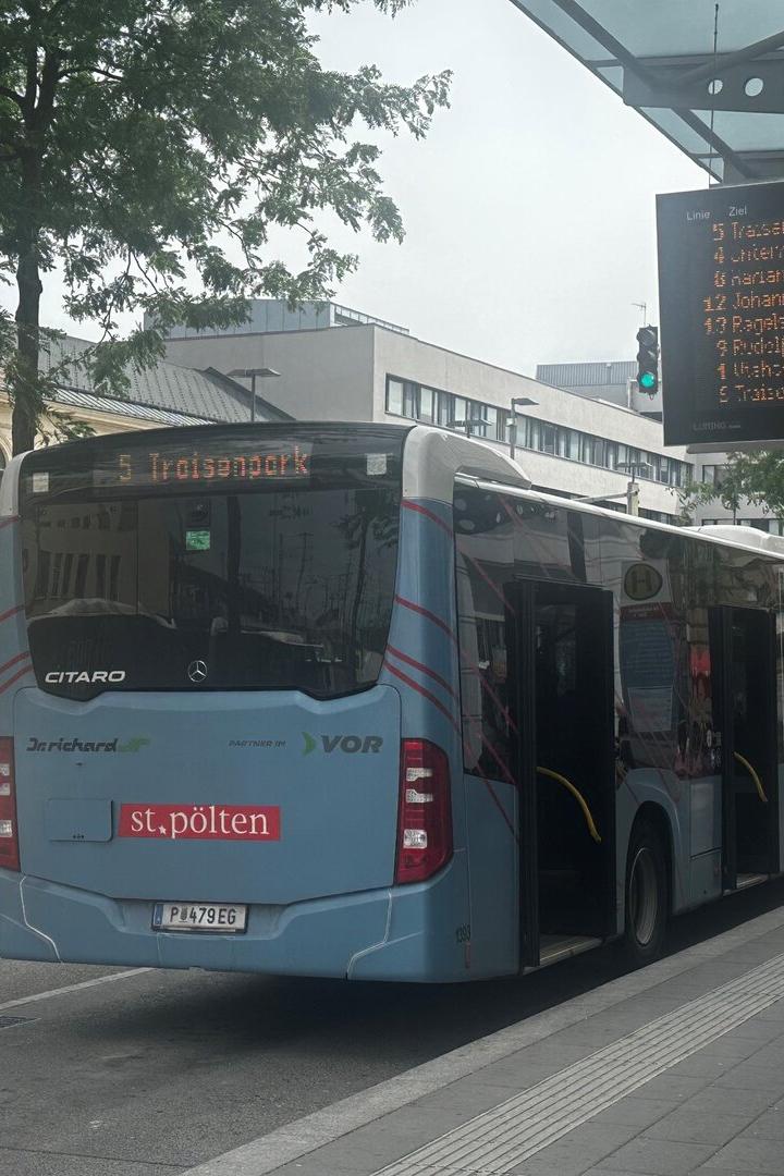 Bushaltestelle in St. Pölten mit wartendem Linienbus und digitaler Abfahrtsanzeige.