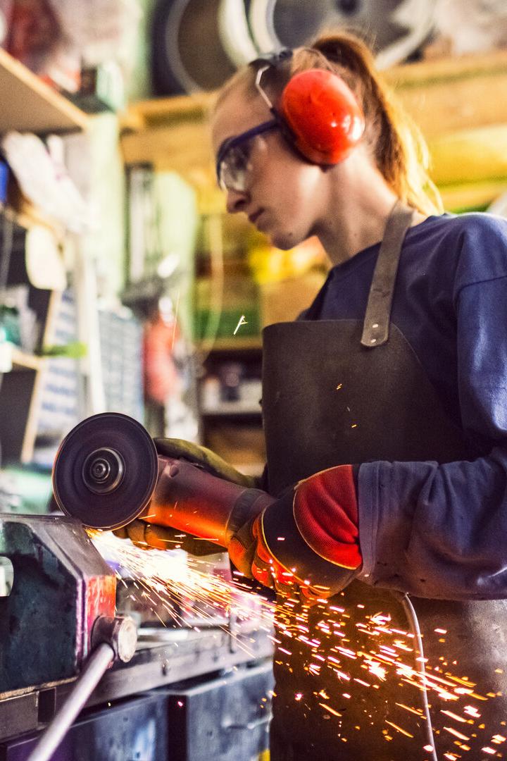 Young woman cutting iron bar in workshop