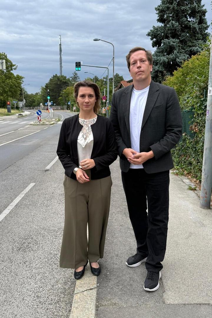 Johanna Zinkl und Patrick Gasselich stehen an einer Straße bei grüner Ampel unter bedecktem Himmel.