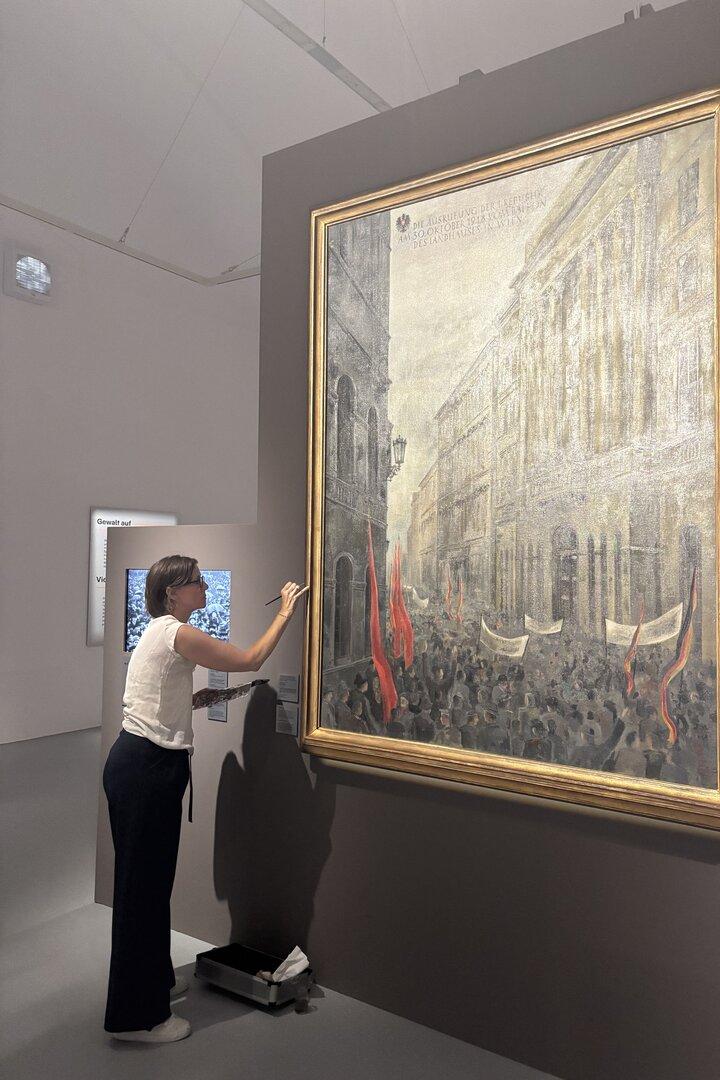 Eine Frau restauriert ein großes historisches Gemälde im Museum.