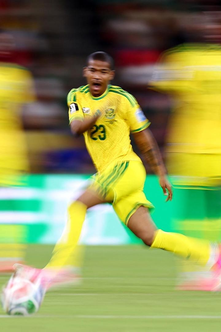 Ein Fußballspieler in einem gelben Trikot mit der Nummer 23 dribbelt bei einem Spiel in Bewegung über das Spielfeld.