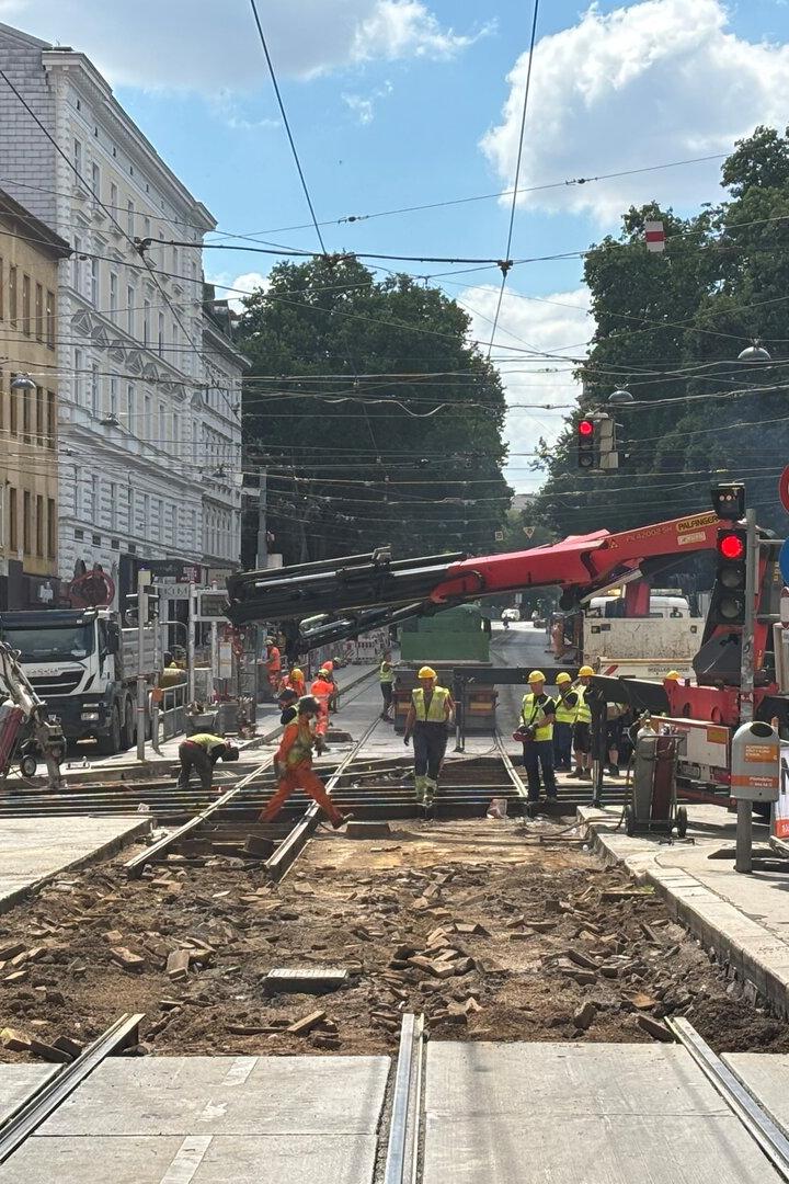 Straßenbahngleise werden von Arbeitern und Baufahrzeugen auf einer gesperrten Stadtstraße erneuert.