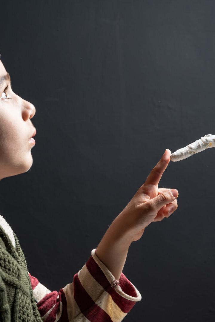 Ein Junge berührt neugierig mit dem Finger die Spitze eines Roboterfingers.