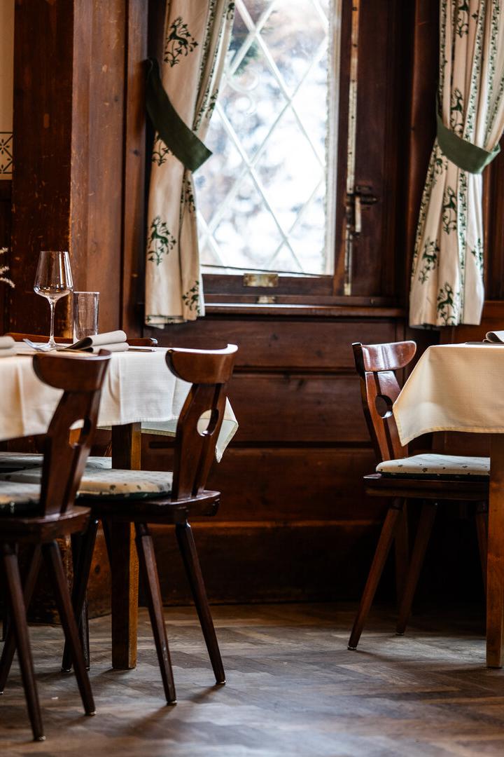 Gemütliches Restaurant mit gedeckten Tischen, Holzstühlen und großen Fenstern.