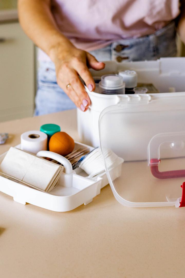 Closeup female hand placing medicament domestic first aid kit. Storage organization emergency supply